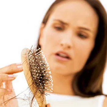 Mulher preocupada com a queda de cabelo na escova